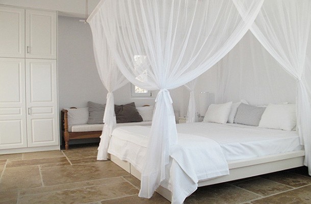 Ліжко з балдахіном Ліжко з балдахіном в спальні в грецькому стилі, блакитні відтінки та натуральні матеріали.