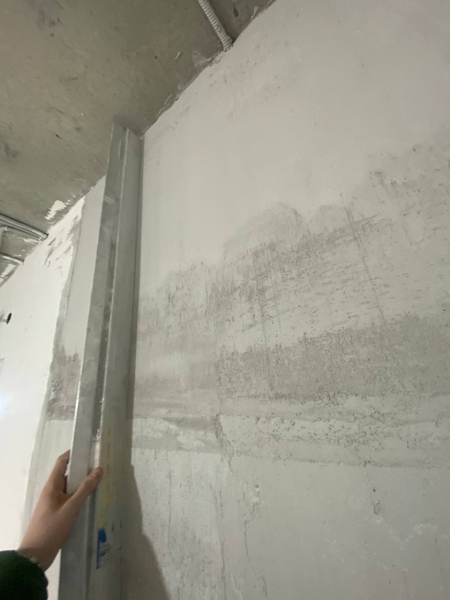 Штукатурка бездоганна Контроль якості штукатурки: перевірка площини стіни двометровим правилом під час технагляду.