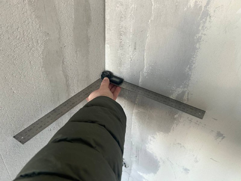 Косинець: ідеальні кути Технічний нагляд: перевірка внутрішніх кутів за допомогою косинця після штукатурних робіт.