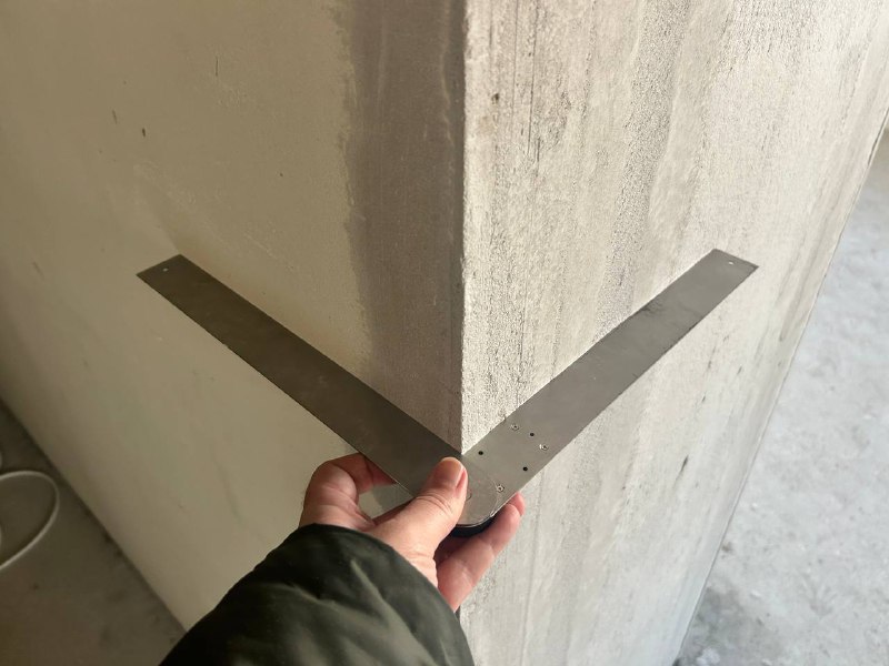 Кутова лінійка: точність Використання кутової лінійки для перевірки зовнішнього кута стіни під час технагляду.