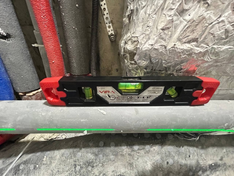 Ухил каналізації: перевірка рівнем Технічний нагляд перевіряє ухил каналізаційних труб будівельним рівнем під час чорнового ремонту.