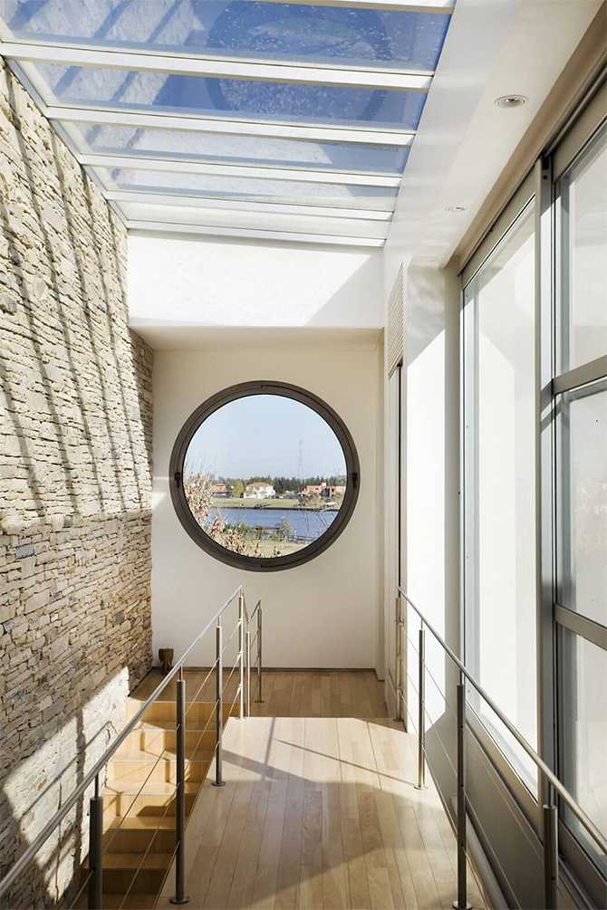 Кругле вікно: Краса Вид з круглого вікна в сучасному будинку на мальовничий ландшафт навколо.