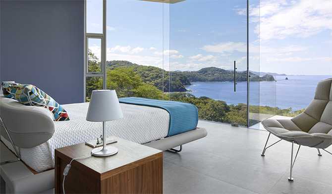 Скляна спальня Скляний будинок з панорамним склінням: сучасна спальня з видом на океан