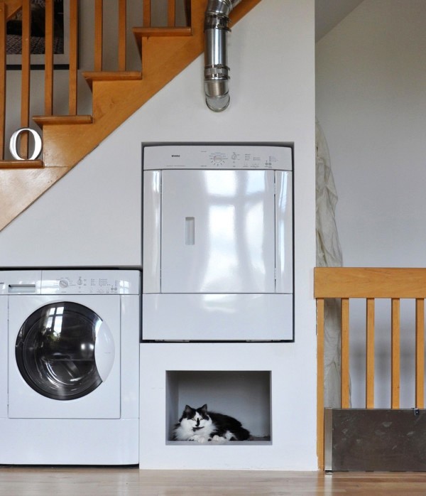 Пральна зона під сходами Пральна та сушильна машини, інтегровані в нішу під сходами в приватному будинку.