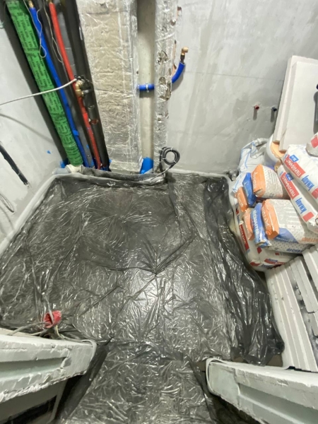 Свіжа стяжка підлоги Свіжа стяжка підлоги під час чорнових робіт, накрита плівкою для правильного висихання.