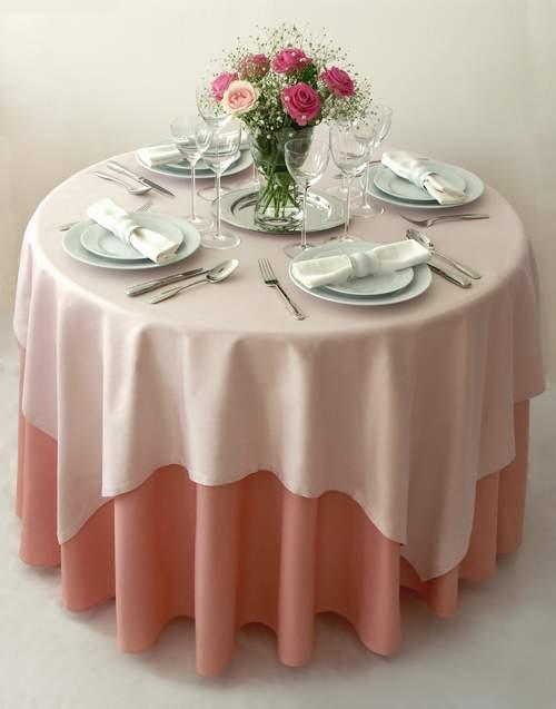 Подвійна елегантність Круглий стіл, накритий білою та синьою скатертинами з візерунком для елегантної сервіровки.