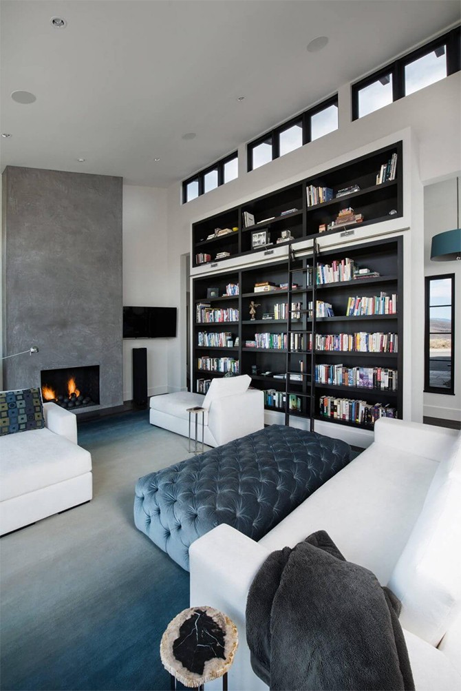 Домашня бібліотека Домашня бібліотека в фермерському будинку з дерев'яними полицями та комфортним кріслом