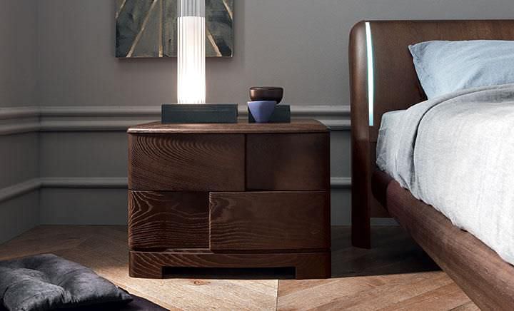 Стиль та затишок Сучасна приліжкова тумбочка з лампою, книгою та годинником у стильній спальні.