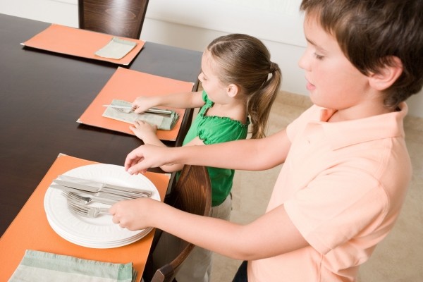 Святкова допомога дітвори Діти допомагають накривати святковий стіл на День народження, створюючи затишну атмосферу.