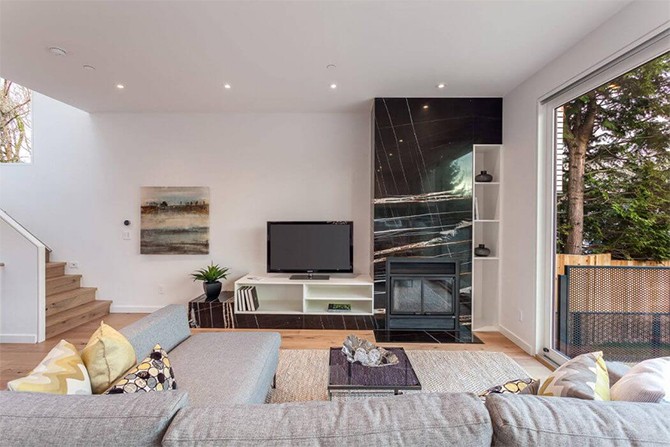 Вітальня в Ванкувері Сучасний трирівневий особняк у Ванкувері: затишна вітальня з панорамними вікнами для відпочинку.