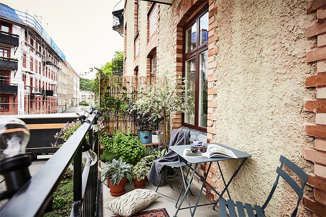 Затишний скандинавський балкон Затишний балкон зі столиком, стільцями та квітами в невеликій квартирі